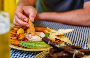 man hand with plate with snacks on table background on bar or pub