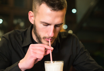 man drinks milk shake with straw in a cafe