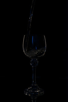 Wine in beautiful vintage crystal glasses on black wall background, with copy space. Wine list, bar drink menu, wine boutique or degustation, square crop concept. Water is poured into a glass