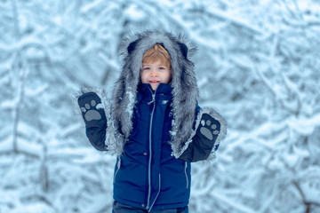 Fototapeta na wymiar Winter landscape of forest and snow with cute child boy. Winter kid posing and having fun. Cute little kid enjoying in the winter park in snow.