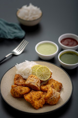 Boneless fried fish served with green sauce and dip