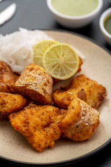 Boneless fried fish served with green sauce and dip