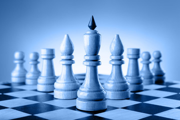 Chessmen King, elephants, rooks and pawns are wedge on the chessboard. Toning in trendy color 2020 classic blue.
