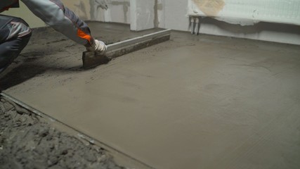 Leveling concrete with trowels, laborer spreading poured concrete. Indication of mortar on the...