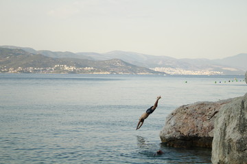 Fototapeta na wymiar Young man diving into the sea from a rock