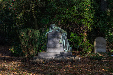 Hamburg, Germany - November 9, 2019: Tomb stone with sculpture in Ohlsdorf Cemetery in the morning in Hamburg city, Germany