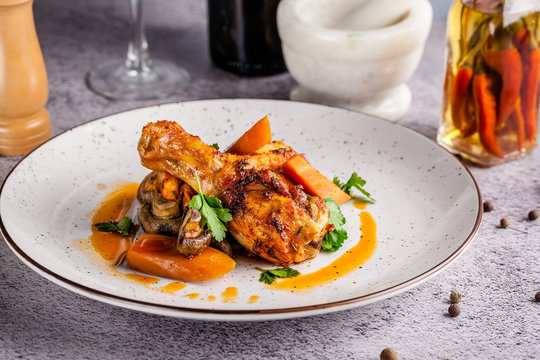 Spanish cuisine. Baked chicken legs with vegetables, mushrooms and carrots. Serving dishes in a restaurant on a white plate. Background image. copy space