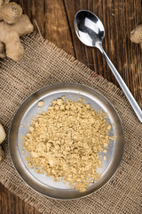 Some Ginger Powder on a vintage wooden table (selective focus; close-up shot)