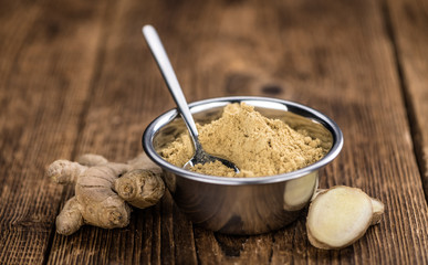 Some Ginger Powder on a vintage wooden table (selective focus; close-up shot)