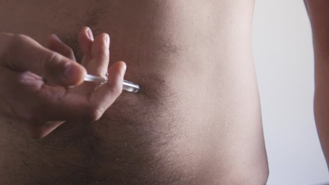 man applying subcutaneous injection in himself, natural light