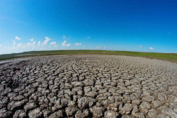 Cracked dry brown earth under the sky with clouds.