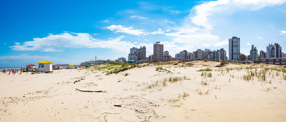 Dunas de areia e o c&eacute;u azul com nuvens na Praia Grande, cidade de Torres, estado do Rio Grande do Sul, Brasil