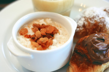 Bowl porridge with raisins and croissant breakfast, close up