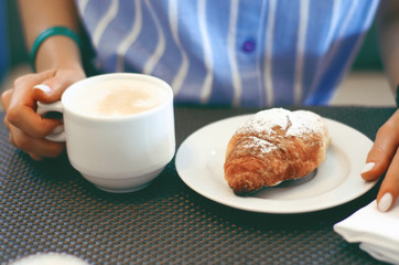 Woman breakfast with croissant and coffee, close up