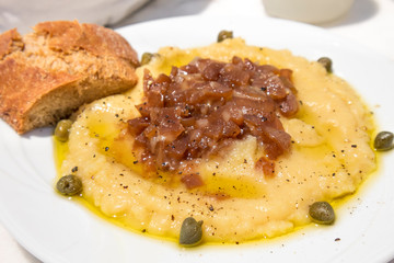 Traditional Fava puree with capers and onions in Santorini taverna, Greece. Fava of Santorini is...