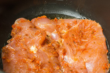 Raw chicken breast fillet marinated in hot spices cooked roasted in slow cooker.