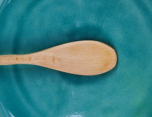 Hunger famine and malnutrition concept - Close up of  isolated wood spoon on empty scratched old china plate