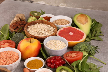 Healthy food clean eating selection: fruit, vegetable, seeds, superfood, cereals, leaf vegetable on rustic background
