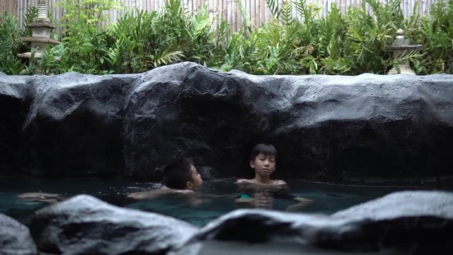 4k Two young asian boy talk and relax in hot water onzen