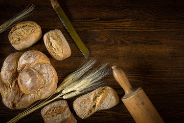 Traditional fresh bread with a blade of wheat on a wooden background.