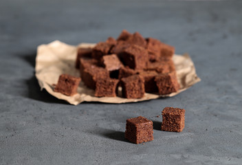 Dessert chocolate cookies cut into cubes, with coffee on a dark gray background