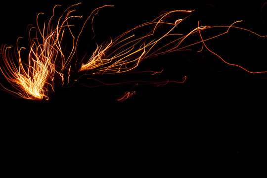 Lichtmalerei mit Funkenflug und feurigen Funken in der Nacht als schwarzem Hintergrund zaubert Leuchtfeuer und Feuerwerk in die Silvesternacht und Silvesterparty