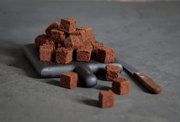 Dessert chocolate cookies cut into cubes, with coffee on a dark gray background