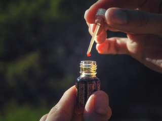 A drop of Oud oil. Arabian oud attar perfume or agarwood oil fragrances in mini bottles.
