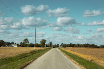 Puffy Clouds, blue skies and a road through farms