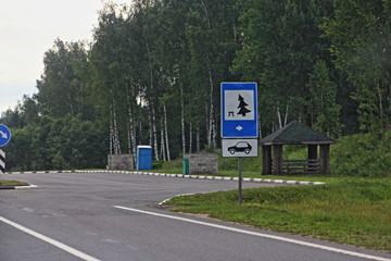 Russian empty free roadside car parking with road sign, blue WC and covered pavilion, place for driver rest on summer day