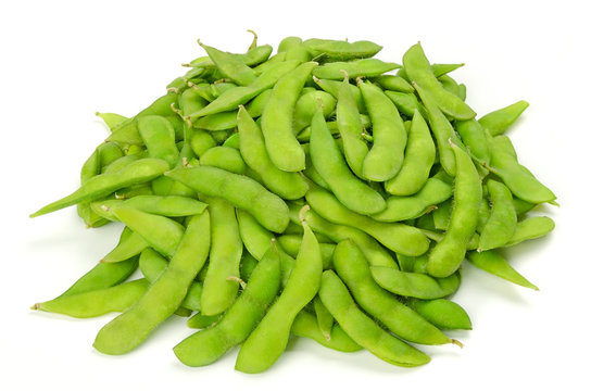 Pile of edamame on white surface. Green soybeans in the pod. Unripe soya beans, Maodou. Glycine max. Legume, edible after cooking. Rich protein source. Closeup, on white background, macro food photo.