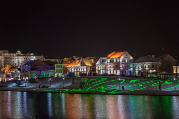Obraz premium Christmas night neon glowing cityscape. Bright city lights reflected in the water. Minsk Belarus. December 31 2019