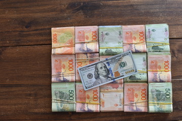 Fototapeta na wymiar 100 dollar bill with Argentine peso bills, symbolic for money exchange rate