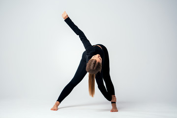 Fitness woman doing stretching exercises in studio. Yoga girl stretches her body