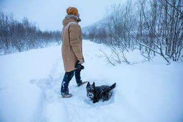 A man photographs his dog on winter walk in the snow