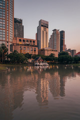 Lake and modern buildings on Sukhumvit Road at sunset, at Benchasiri Park, in Bangkok, Thailand