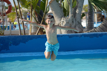 Naklejka premium Caucasian boy having fun making fantastic jump into swimming pool at resort.