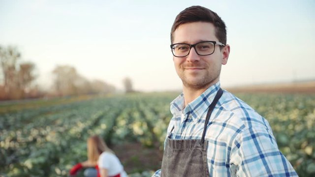 Handsome european happy man farmer holding wood box with cabbage, looking into the camera and smiling, feeling good, happy. Close up, slow motion. Shoot on ARRI ALEXA.