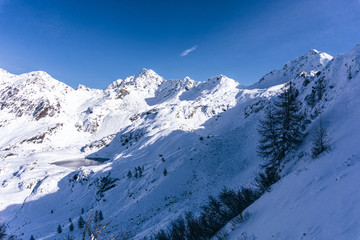 Fototapeta premium The snowy mountains, the nature and the landscape of the Valtellina after the first snowfall of the season in the Alps, near the town of Tartano, Italy - November 2019.