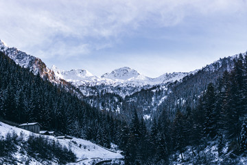 The snowy mountains and the Valtellina landscape at sunset after the first snowfall of the season in the Alps, near the town of Tartano, Italy - November 2019.