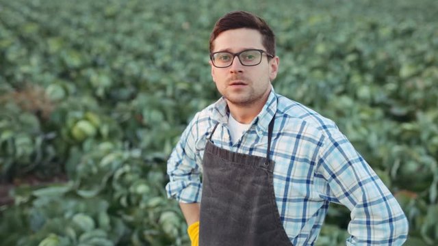 Portrait of tired and happy smart young man farmer looking into the camera and smiling, feeling good, happy. Close up, slow motion. Shoot on ARRI ALEXA.