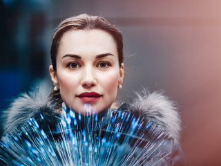 Portrait of young woman with a bunch of glowing optical fibers in her hands look