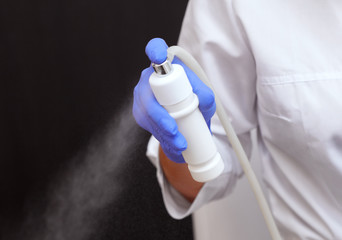 The cosmetologist holds a nozzle for a steam generator, for steaming the skin of the face before the procedure for cleansing the face from acne and blackheads. Cosmetology concept.