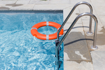 Orange lifebuoy pool ring float on blue water - Life ring in swimming pool