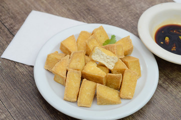 Fried tofu meal with soy sauce on wooden table