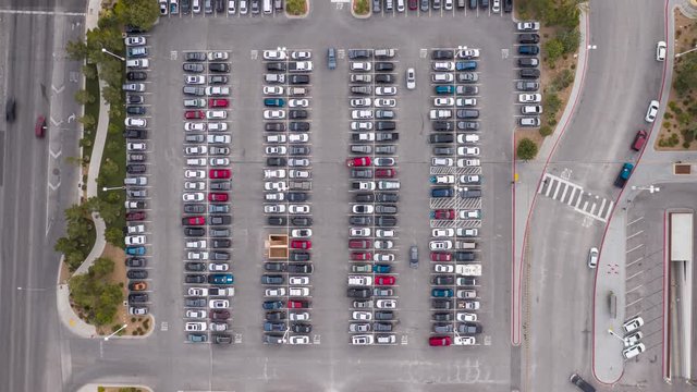 Aerial timelapse of cars driving in a busy parking lot and intersection traffic