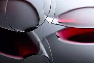 Glasses of red wine on a black reflective background.