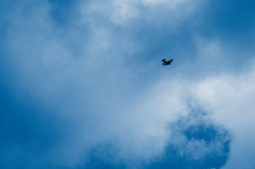 green airplane flying high in a cloudy blue sky. long-range shooting.  toned  in classic blue trendy color of the year 2020