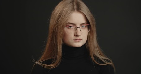 Determined young woman in black outfit and spectacles shaking head, negative reaction