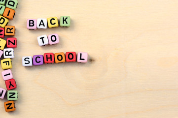 Blocks with letters back to school on light brown wooden texture background